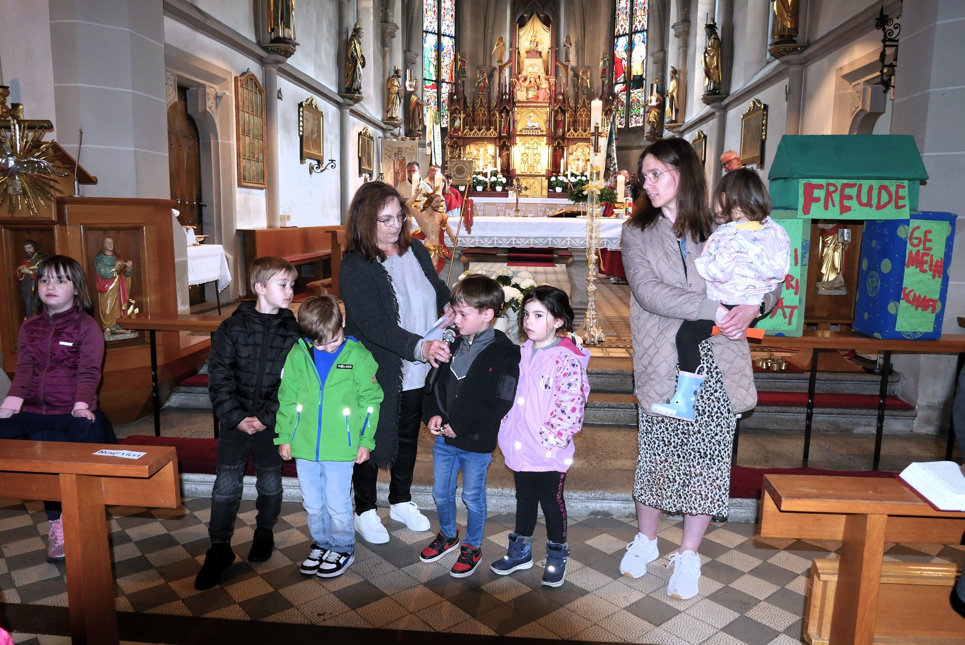 Die Kinder bringen die Fürbitten vor, rechts das Haus aus Bausteinen – Freude, Gemeinschaft und Solidarität